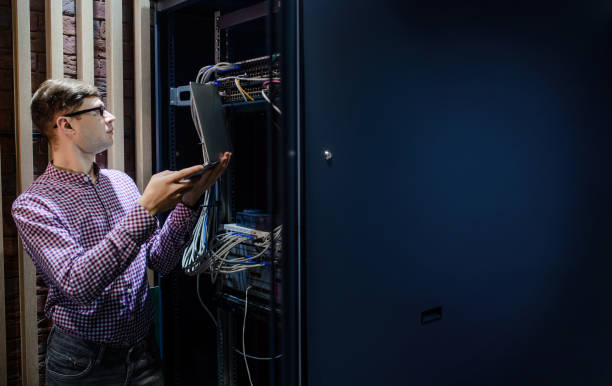 in the server room a technician/ it engineer/ hold the notebook - computer plan fiber optic engineer imagens e fotografias de stock