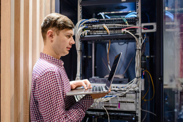 in the server room a technician/ it engineer/ hold the notebook - computer plan fiber optic engineer imagens e fotografias de stock