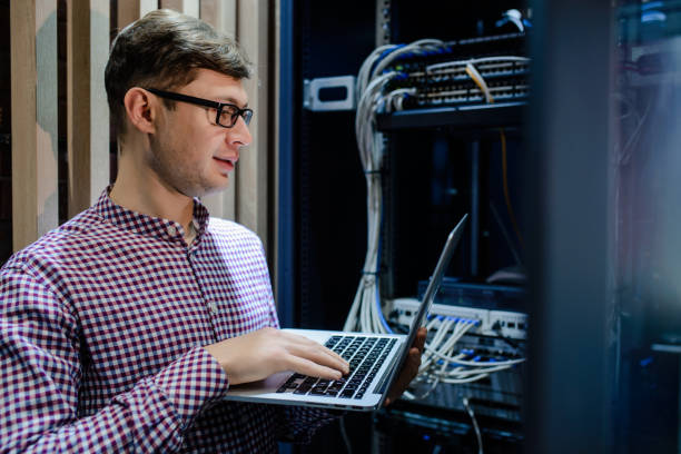 in the server room a technician/ it engineer/ hold the notebook - computer plan fiber optic engineer imagens e fotografias de stock