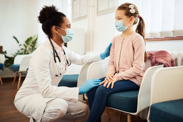 bambina e dottoressa nera che indossa maschere per il viso mentre parla nella sala d'attesa della clinica medica. - dentist family doctor dental hygiene foto e immagini stock