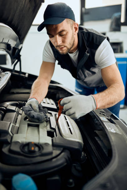 istock Young mechanic checking oil level while maintaining car engine at auto repair workshop. 1361355525