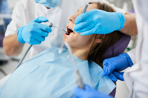 Primer plano del dentista limpiando los dientes de la adolescente durante el procedimiento dental en el consultorio del dentista. photo