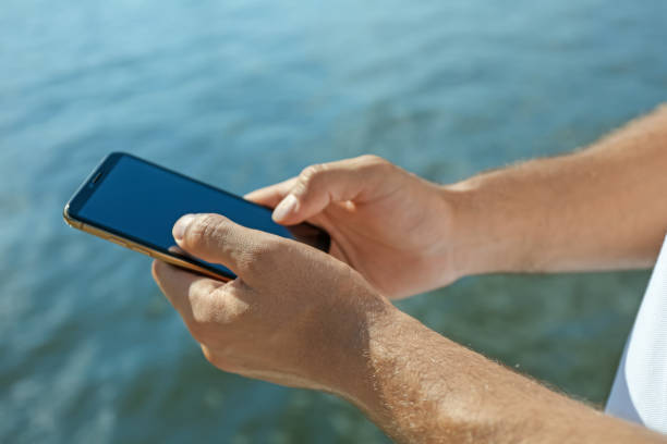istock Man using modern mobile phone near river, closeup 1361355612