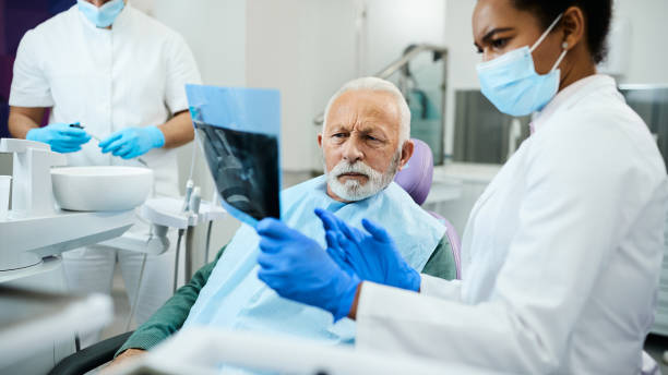 歯科医院での予約時に歯科x線を分析する先輩男性と彼の歯科医。 - 歯 写真 ストックフォトと画像