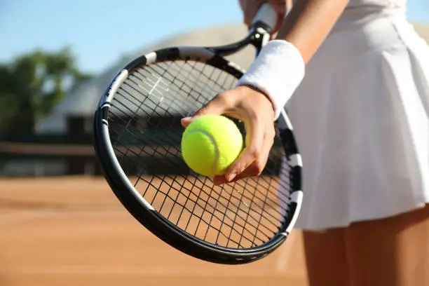 Photo of Sportswoman preparing to serve tennis ball at court, closeup