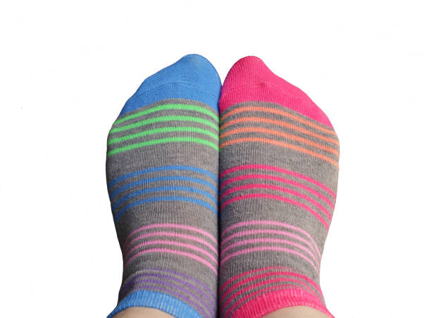 Grey mismatched socks with bright pink and blue stripes on a white background, photo cut out.