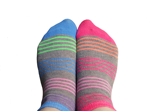 Grey mismatched socks with bright pink and blue stripes on a white background, photo cut out.