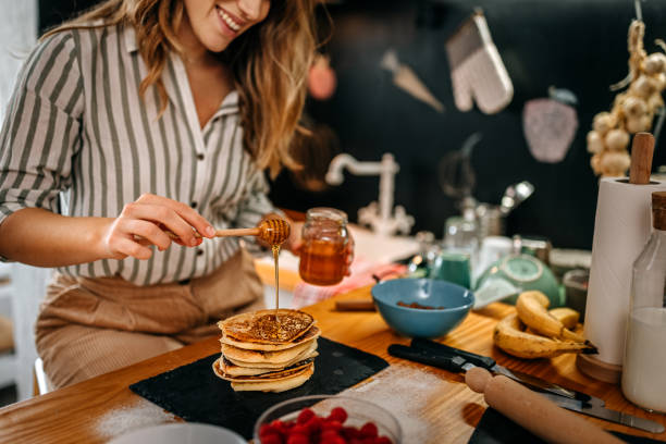 Women food blogger adding honey in pancakes