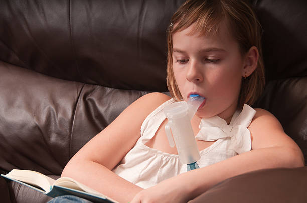 Respiratory inhaled antibiotic therapy Close up of adorable young girl doing respiratory antibiotic therapy while reading a book to pass the time. staphylococcal enterotoxicosis stock pictures, royalty-free photos & images