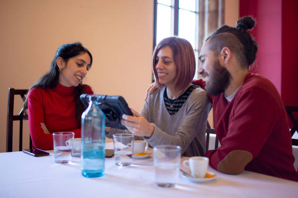 istock friends in restaurant watching the cell phone 1361365485