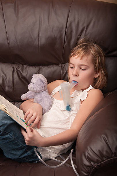 Respiratory inhaled antibiotic therapy with best friend and a book Close up of adorable young girl doing respiratory antibiotic therapy with aerosol compressor inhaled antibiotic with her teddy bear and a book to pass the time. staphylococcal enterotoxicosis stock pictures, royalty-free photos & images