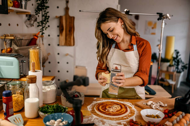istock Woman grating cheese on pizza base while recording video 1361367971