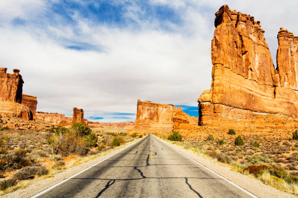 Arches National Park Two lane highway along the natural beauty of Arches National Park in Utah. single yellow line sunlight usa utah stock pictures, royalty-free photos & images