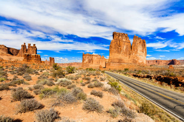 Arches National Park Two lane highway along the natural beauty of Arches National Park in Utah. single yellow line sunlight usa utah stock pictures, royalty-free photos & images