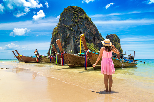 Beautiful tourist woman near traditional longtail boat in Phra Nang  Beach, Thailand