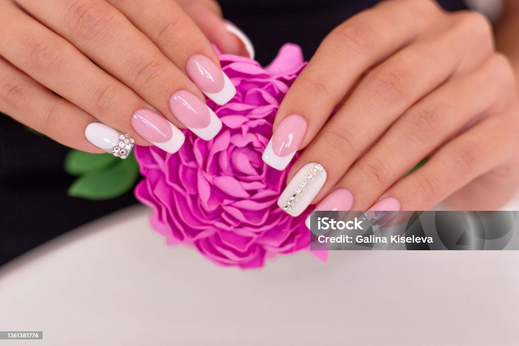 Beautiful female hands with french manicure Close up view of beautiful female hands with luxury french manicure nails holding pink peony flower Fingernail Stock Photo