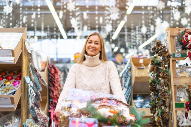 shopping de décoration de noël. une femme caucasienne choisit un décor du nouvel an dans un centre commercial - pull cart photos et images de collection