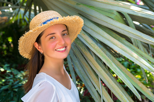 Young beautiful woman  is posing among large leaves of tropical palm tree