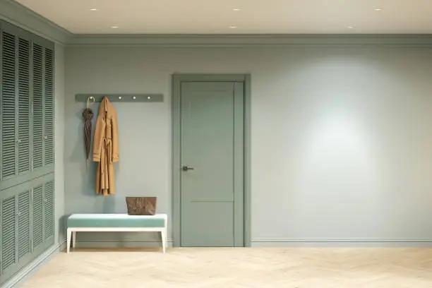 Photo of Green entrance hall in a modern classic style with a blank wall illuminated by a spotlight, an entrance door, a clothes hanger over a bench, a built-in wardrobe, a parquet floor. Front view.