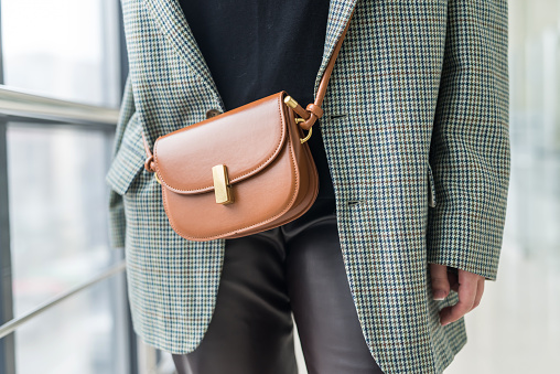 hermosa mujer joven con ropa elegante con un bolso de cuero marrón en una correa. photo