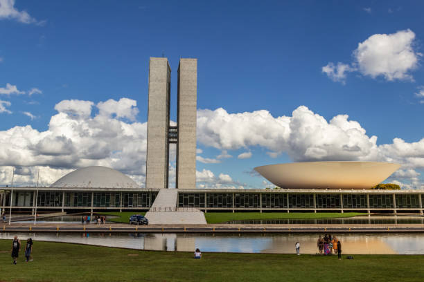 Brasilia, Federal District, Brazil – December 25, 2021: National Congress Palace with reflection in the water mirror, on a clear day with cloudy sky. The National Congress Palace is a work of architect Oscar Niemeyer.