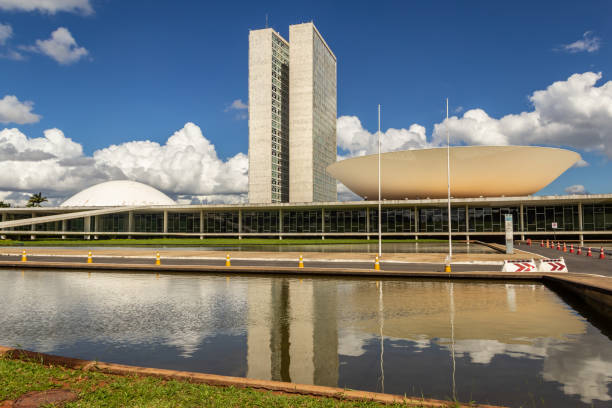 Nacional Congress Palace. Brasilia, Federal District, Brazil – December 25, 2021: National Congress Palace with reflection in the water mirror, on a clear day with cloudy sky. The National Congress Palace is a work of architect Oscar Niemeyer. congress stock pictures, royalty-free photos & images