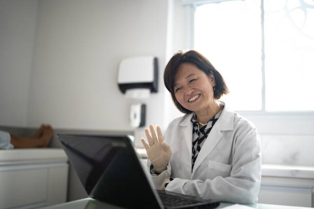 doctor doing a telemedicine using laptop at a medical clinic - doctor patient greeting talking imagens e fotografias de stock