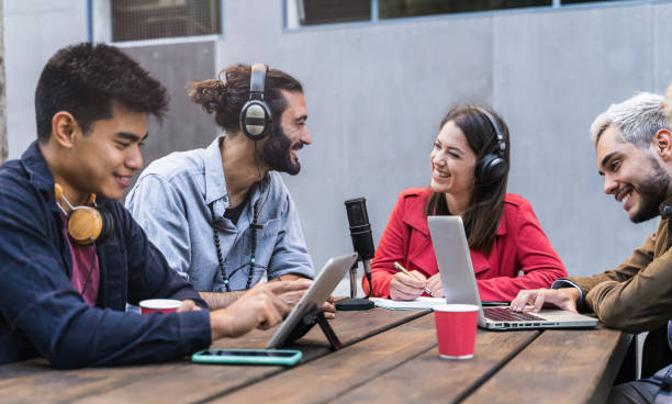 istock Creative friends working with digital technology and laptops outdoors, recording podcast 1361394486