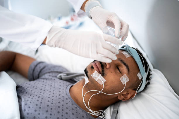 medico che prepara il paziente a letto per la polisonnografia (studio del sonno) - electrode foto e immagini stock