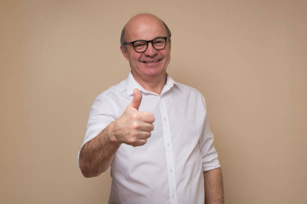 Cheerful senior man giving thumb up approving your choice stock photo