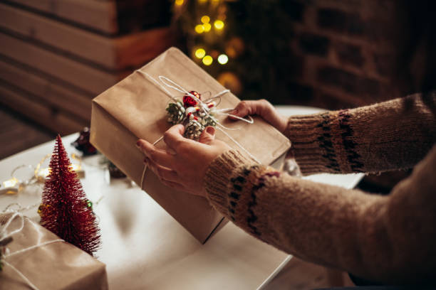 istock Woman s hands wrapping Christmas gift boxes, close up. Unprepared presents on white table with decor elements and items Christmas or New year DIY packing Concept. 1361397973