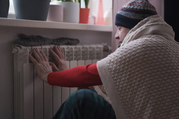 Man feeling cold at home with home heating trouble stock photo