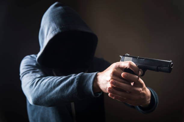 istock holding a gun on a dark background 1361400119