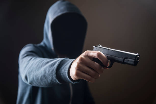 istock holding a gun on a dark background 1361400124