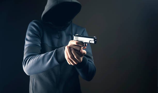 holding a gun on a dark background a man holding a pistol on a dark background gunman stock pictures, royalty-free photos & images