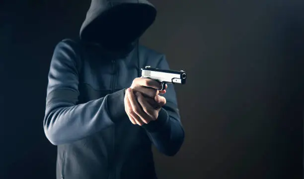 a man holding a pistol on a dark background