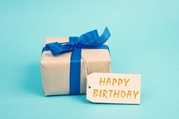 istock Small gift box with a ribbon on a blue colored background, happy birthday present 1361401014