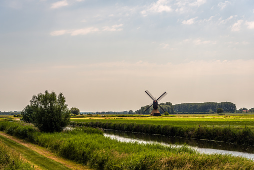 Polder landscape with the Uitwijkse Molen, a thatched hollow post mill, near the Dutch village of Sleeuwijk, province of North Brabant. The mill was built in the year 1700 and is now a national monument.