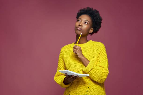 istock Stylish pensive african american girl pondering idea to write into notebook, thinking over business plan, to-do list 1361403684