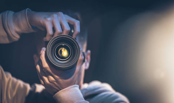 카메라를 들고 있는 한 남자 사진작가가 어두운 복사 공간에서 사진을 찍습니다. - photographing 뉴스 사진 이미지