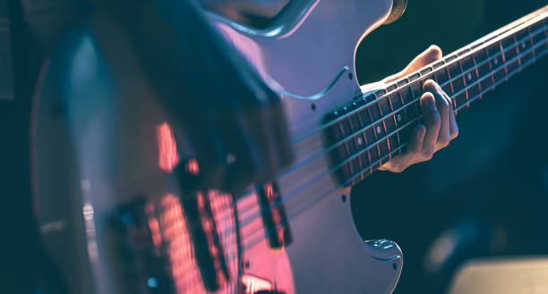 Close-up of a man playing the bass guitar. Close-up of a man playing bass guitar at a concert in the dark. bass guitar stock pictures, royalty-free photos & images