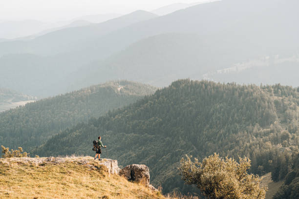 istock Young man hikes along grassy mountain ridge 1361408135