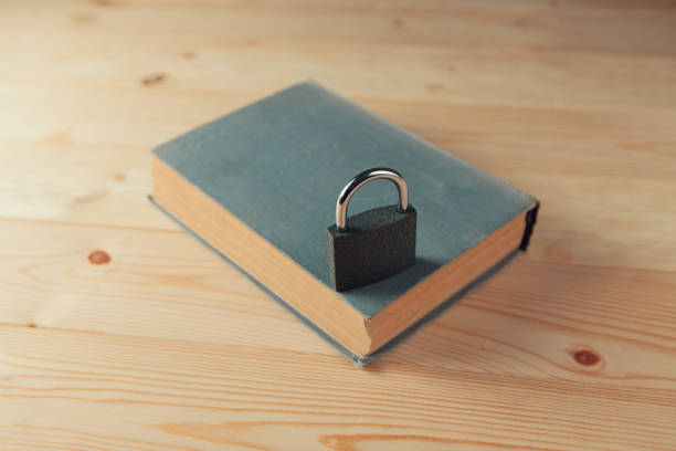 On an old book with clasps, there is an old key made of metal. Antique objects on a dark wooden background.