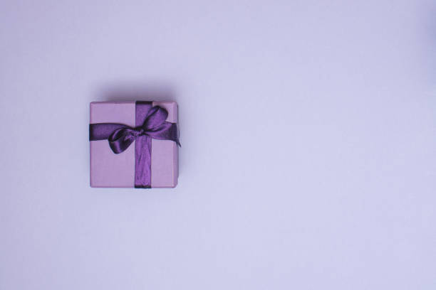 istock Purple gift box with ribbon on pastel purple background with copy space. Creative realistic minimal gift for Christmas or Holiday giving. 1361409384