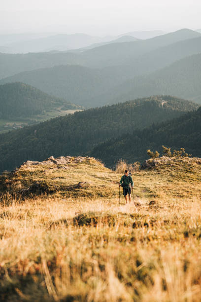 istock Young man hikes along grassy mountain ridge 1361409674