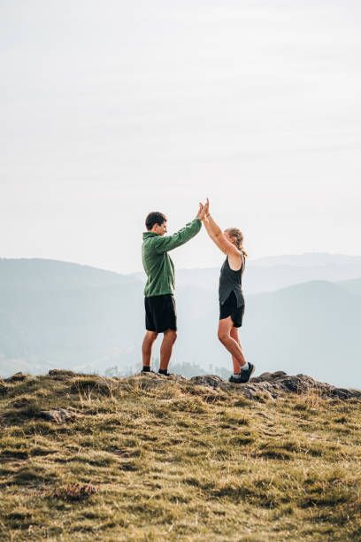 randonneurs high-five sur la crête herbeuse de la montagne - hiking young women outdoors t shirt photos et images de collection