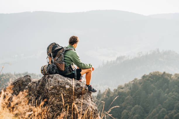 istock Hiker relaxes on grassy mountain ridge 1361413960