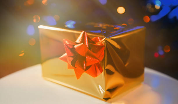 istock New Year's gift in shiny packaging by the Christmas tree. 1361415389