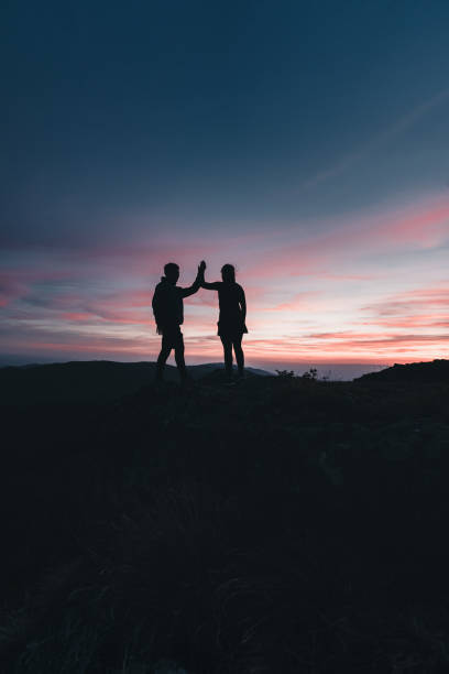 istock Hikers high-five on mountain ridge, at sunrise 1361416881