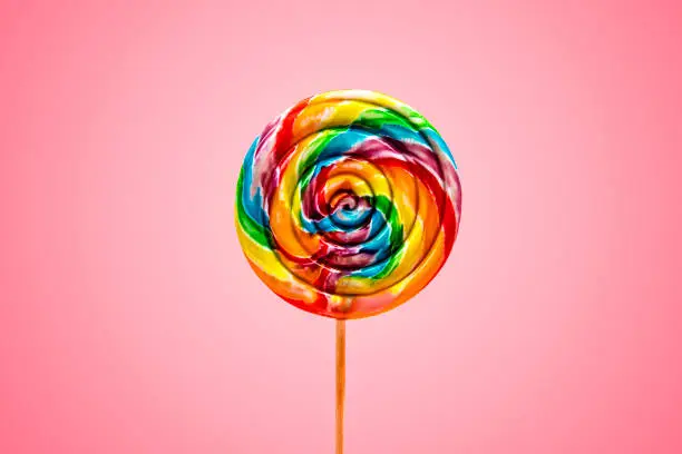 This is a fun bright colorful swirly large lollipop on a pink background